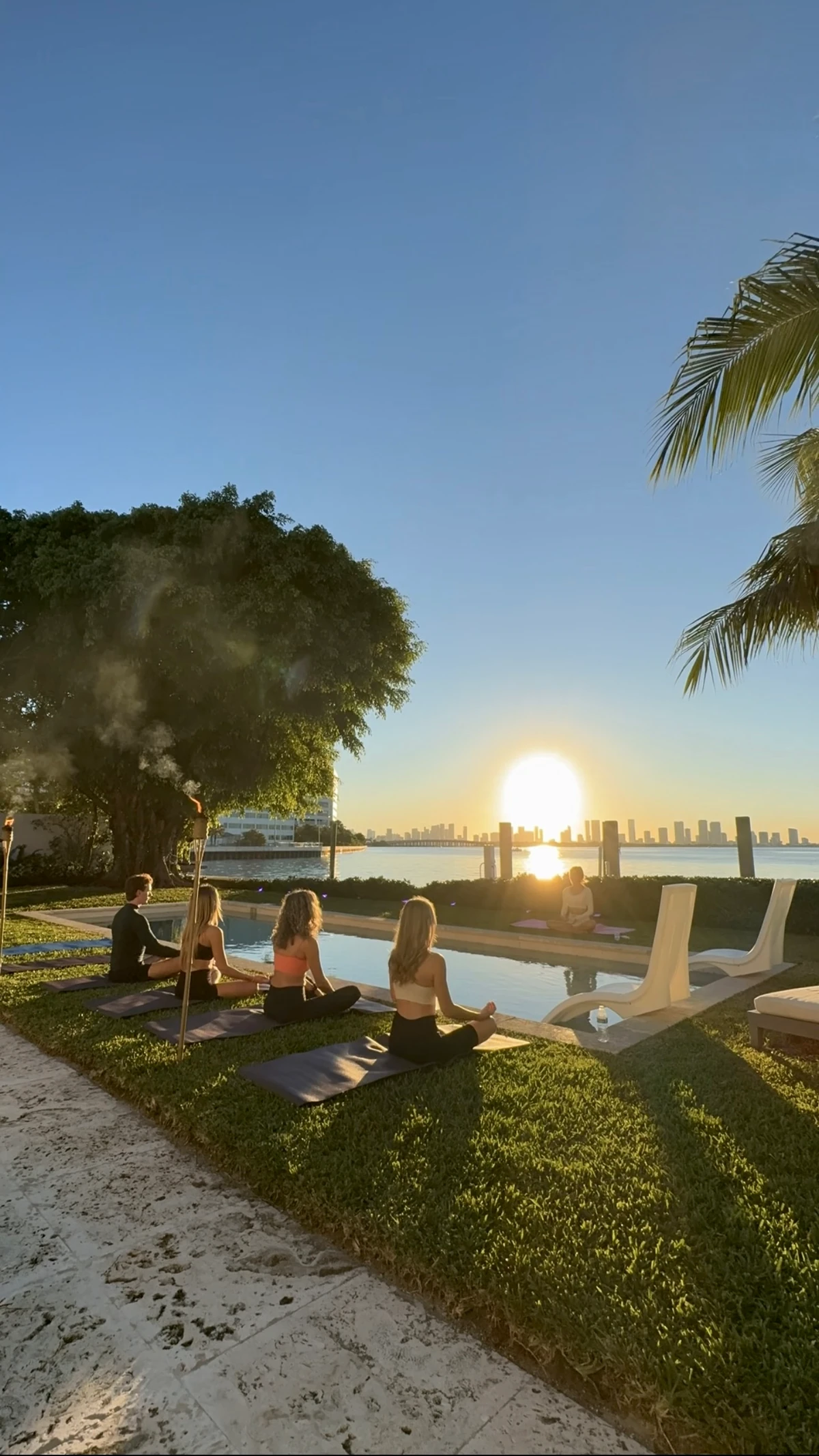 A group practicing together beside the water at sunset