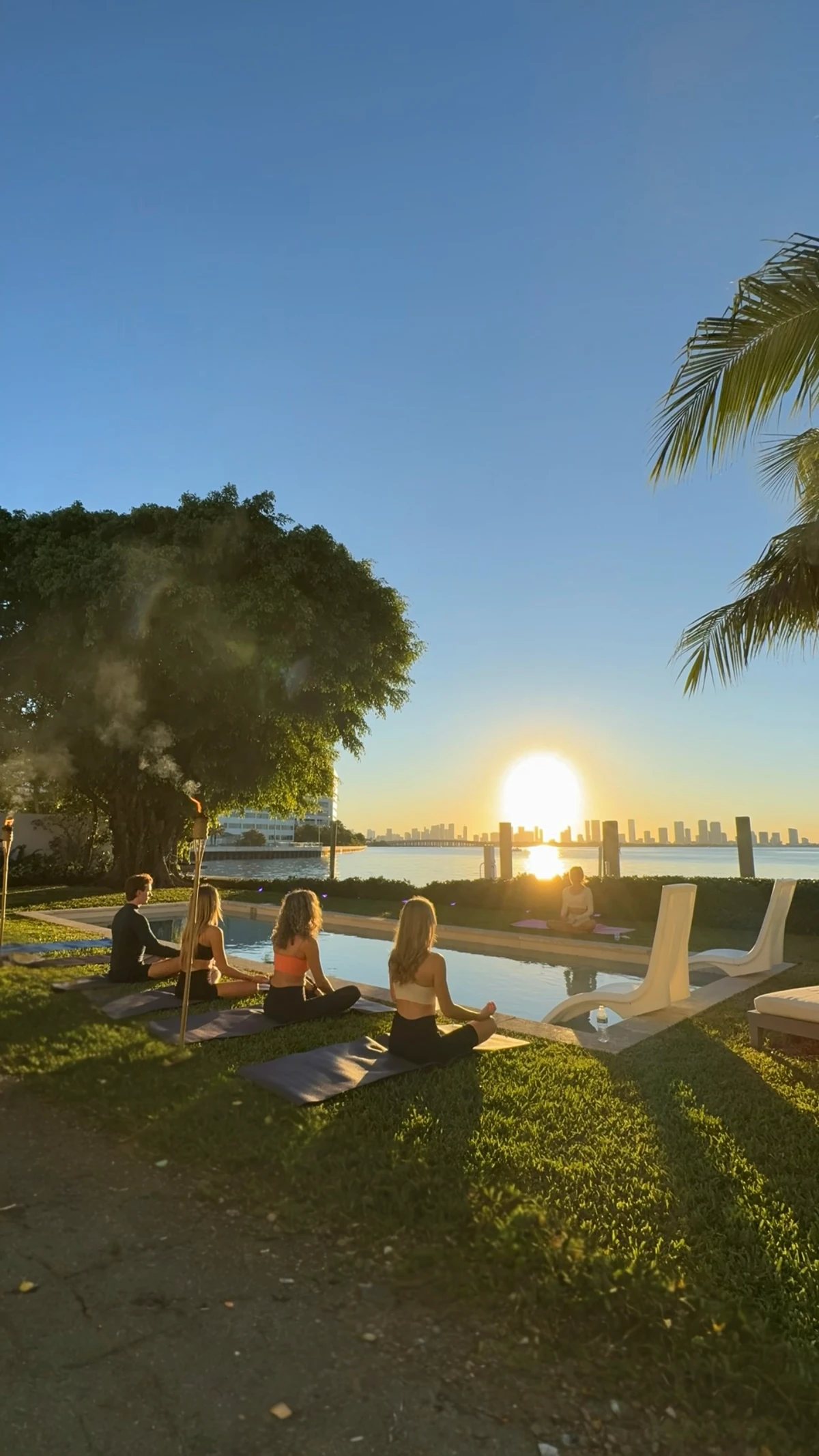 A group practicing together beside the water at sunrise